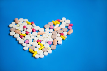 Pills in a heart shape on a blue background.