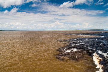 The Meeting of Waters (Encontro das Aguas) is the confluence between the Rio Negro river, with dark...