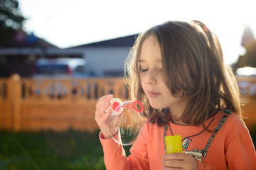 Cute little girl making soap bubbles in the garden