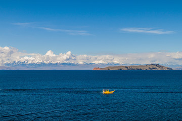 Cordillera Real mountain range behind Titicaca lake, Bolivia. Isla de la Luna and a traditional boat also visible.