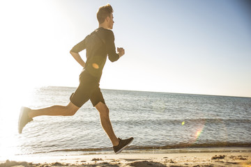 Fototapeta na wymiar Running man. Male runner jogging during the sunrise on beach