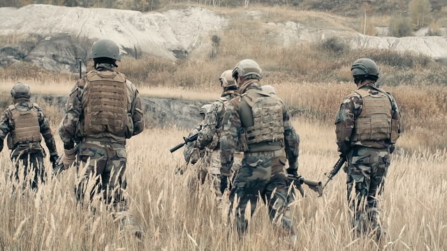 Rear view of ranger team walking through a field in slow motion 