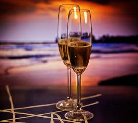 Champagne glasses on tropical beach at sunset - exotic New Year