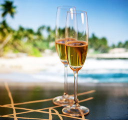 Champagne glasses on tropical beach at sunset - exotic New Year