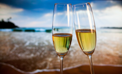 Champagne glasses on tropical beach at sunset - exotic New Year