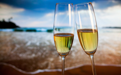 Champagne glasses on tropical beach at sunset - exotic New Year