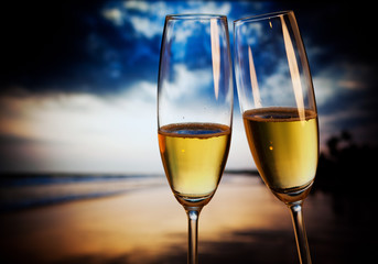 Champagne glasses on tropical beach at sunset - exotic New Year
