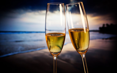 Champagne glasses on tropical beach at sunset - exotic New Year
