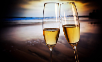 Champagne glasses on tropical beach at sunset - exotic New Year