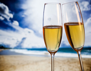 Champagne glasses on tropical beach at sunset - exotic New Year