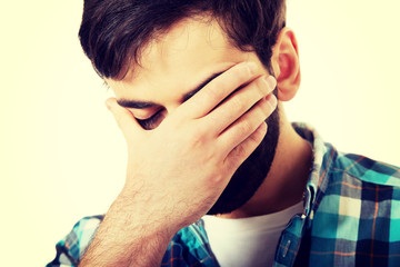 Young depressed man touching his face.