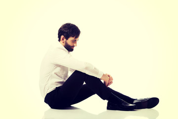 Young businessman sitting on the floor. 
