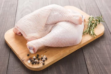 Fototapeten Raw chicken leg on cutting board on wood table © Delicious