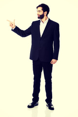 Happy businessman points to the left.
