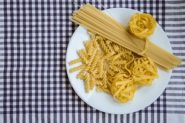Noodles in a white plate on a checkered tablecloth