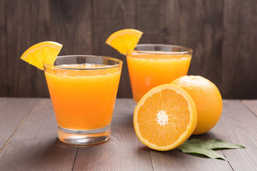 Fresh orange juice and oranges on wooden table