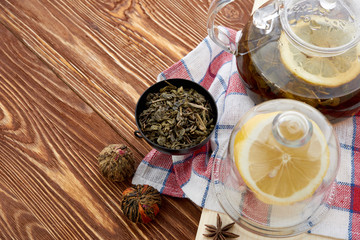 Ripe lemon, cinnamon and fruit drink in glass teapot on wooden background
