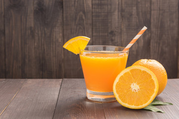 Fresh orange juice and oranges on wooden table