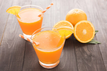 Fresh orange juice and oranges on wooden table