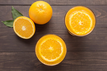 Fresh orange juice and oranges on wooden background