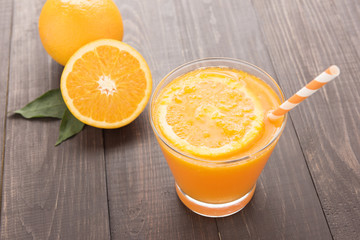 Fresh orange juice and oranges on wooden table