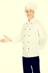 Happy mature chef with welcome gesture