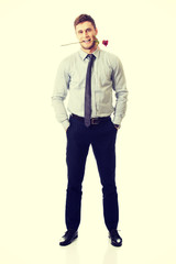 Handsome man holding red rose in his mouth.