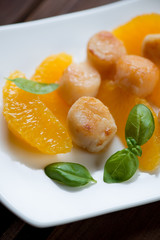 Close-up of roasted sea scallops served with orange fillet