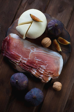 Sliced cheese with fresh figs, walnuts and ham, above view