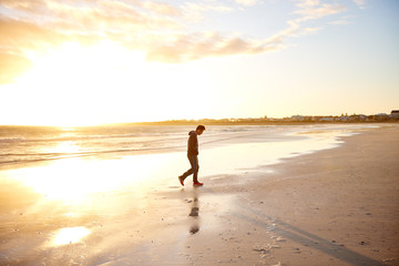 Silhouette of a man walking on a beautiful sunrise beach