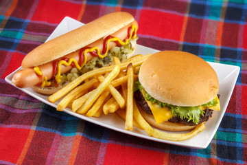 Hot dog , french fries and cheese burger on plate , fast food lunch on red fabric surface - 94498434