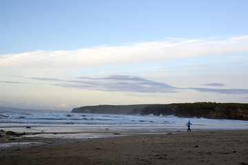 woman walking at rocky cold beach