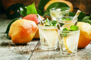 Pear cocktail with soda, fruit slices and mint on an old wooden