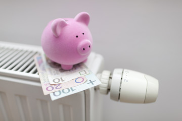 Piggy bank with polish money on radiator. Energy saving concept.
