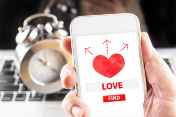 Hand holding mobile with red heart and find love word on screen