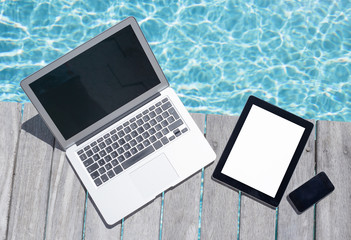 Laptop, tablet computer and mobile phone by the pool