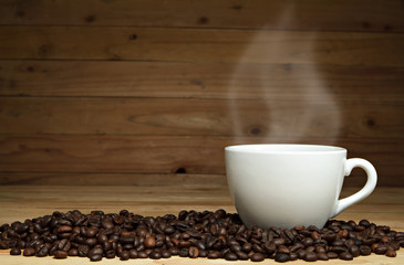 Coffee cup and coffee beans on wooden background.
