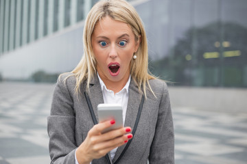 Surprised business woman looking at her smartphone