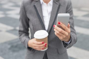 Business woman drinking coffee and using smartphone