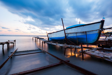 Fototapeta na wymiar Wooden boat in a fishing village at sunset
