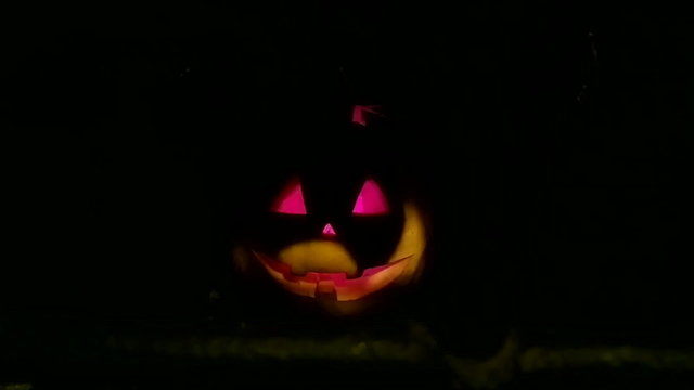 Dark night a lantern in the shape of a pumpkin on Halloween. Flickers in the darkness.