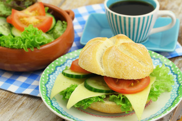 Lunch consisting of cheese roll, green salad and up of coffee
