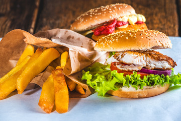 Fish burger with rustic chips on white paper for takeaway