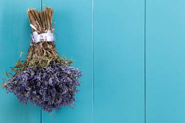 Ein Bündel Lavendel hängt zum Trocknen auf einer mediterranbllauen Holzwand