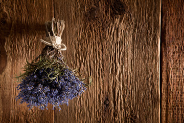 Ein Strauß Lavendel hängt zum Trocknen auf einer rustikalen Holzwand