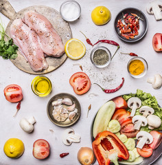 Turkey breast On a cutting board with herbs different fruits and vegetables Cucumbers mushrooms tomato salad pepper and lemon in a frying pan on rustic wooden background top view close up