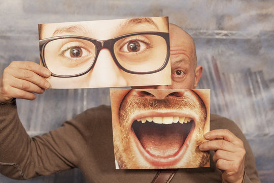 bald man holding a card with a big smile and big glasses on it