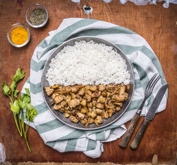 cooking concept Cooked turkey with onions and spices lined with half the rice in a pan on a striped napkin on rustic wooden background top view close up