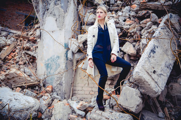 Blonde in the coat on the ruins of the house, beauty