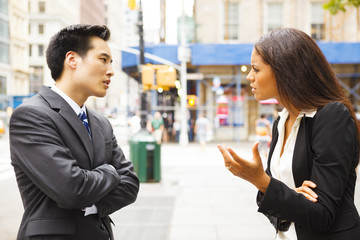 A man and a woman arguing on a city street.